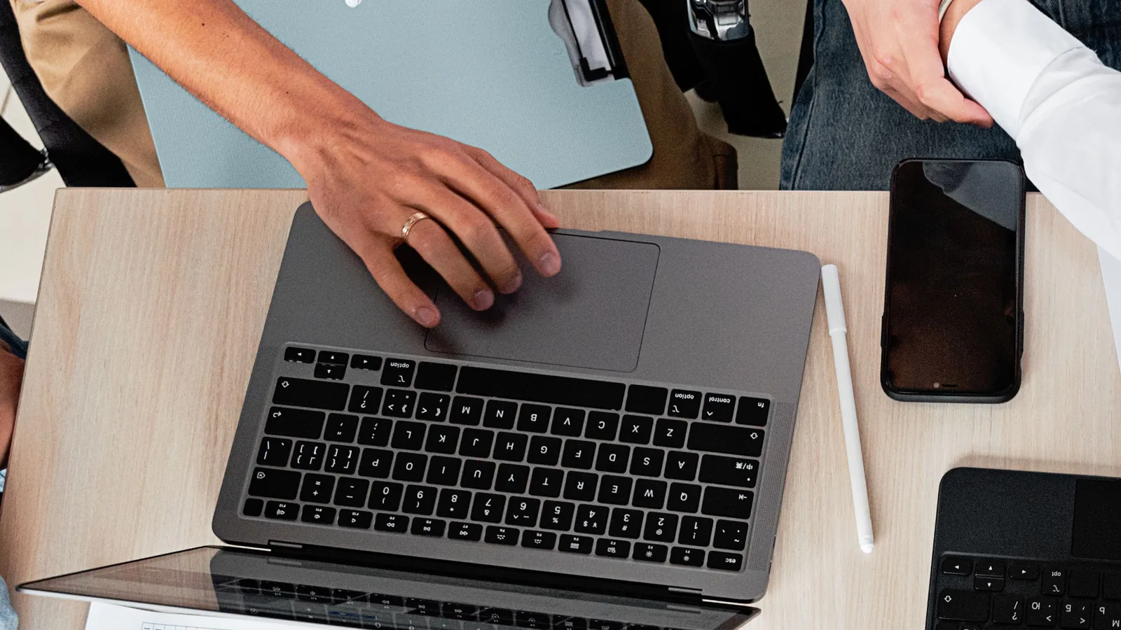 Blick von oben auf einen Schreibtisch mit aufgeklapptem Notebook und daneben liegendem Smartphone